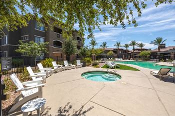 A pool area with chairs and a building in the background.